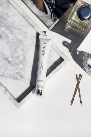 Alpha-H Absolute Eye Complex su marmo con mollette per capelli
