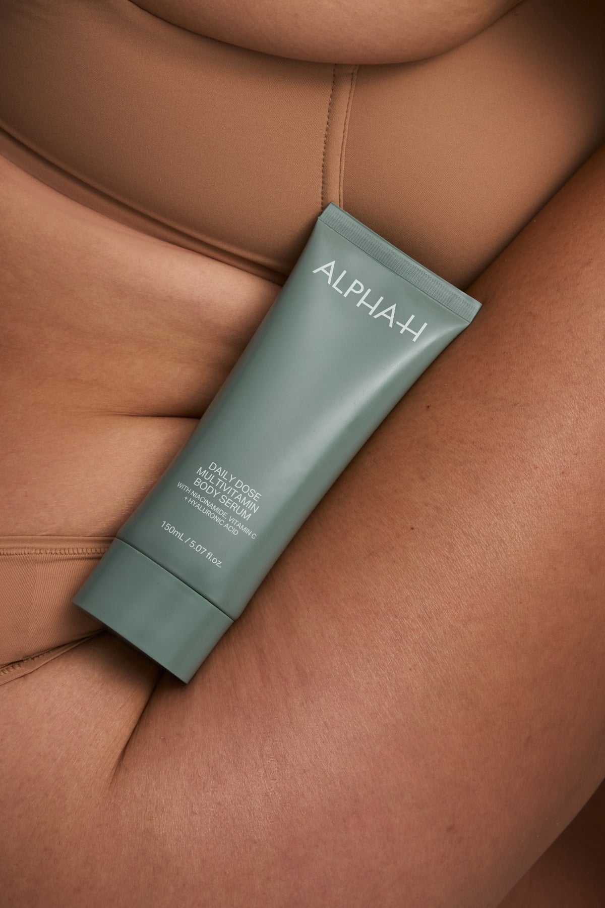 Alpha-H Daily Dose Multivitamin Body Serum tubo accanto al braccio