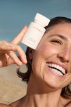 Alpha-H Liquid Gold Exfoliating Treatment modella con il flacone al mare