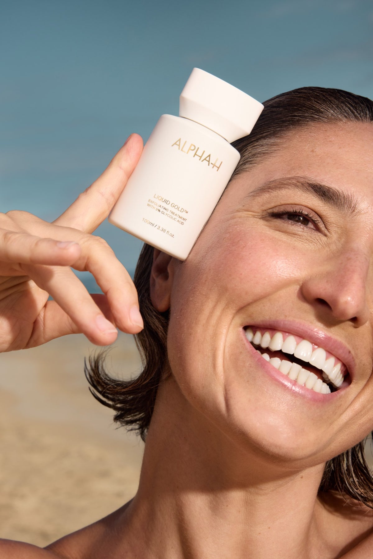 Alpha-H Liquid Gold Exfoliating Treatment modella con il flacone al mare