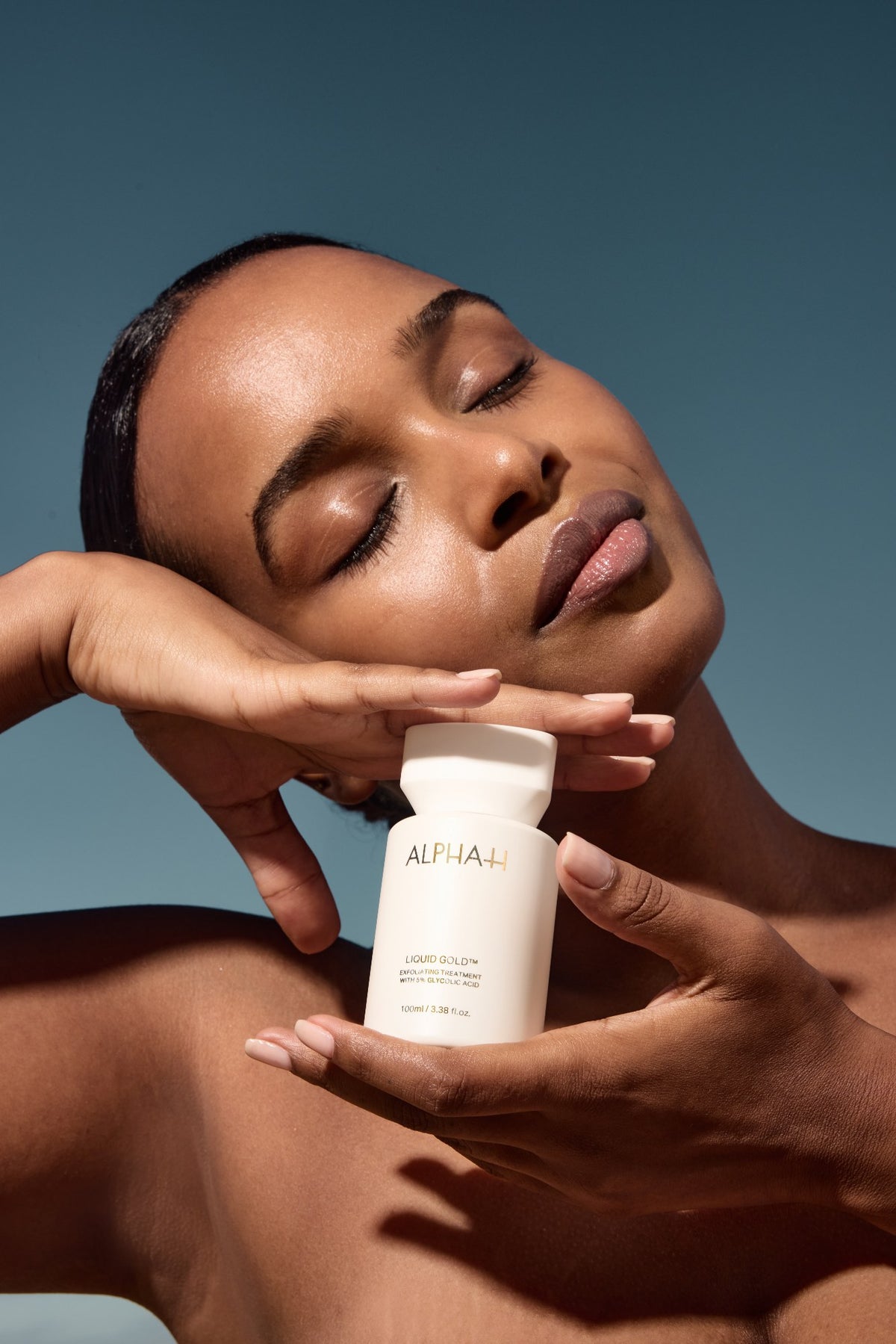 Alpha-H Liquid Gold Exfoliating Treatment modella con il flacone alla luce del sole
