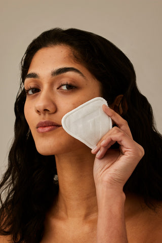 Alpha-H Re-usable Bamboo Cotton Pads modella con dischetto accanto al viso
