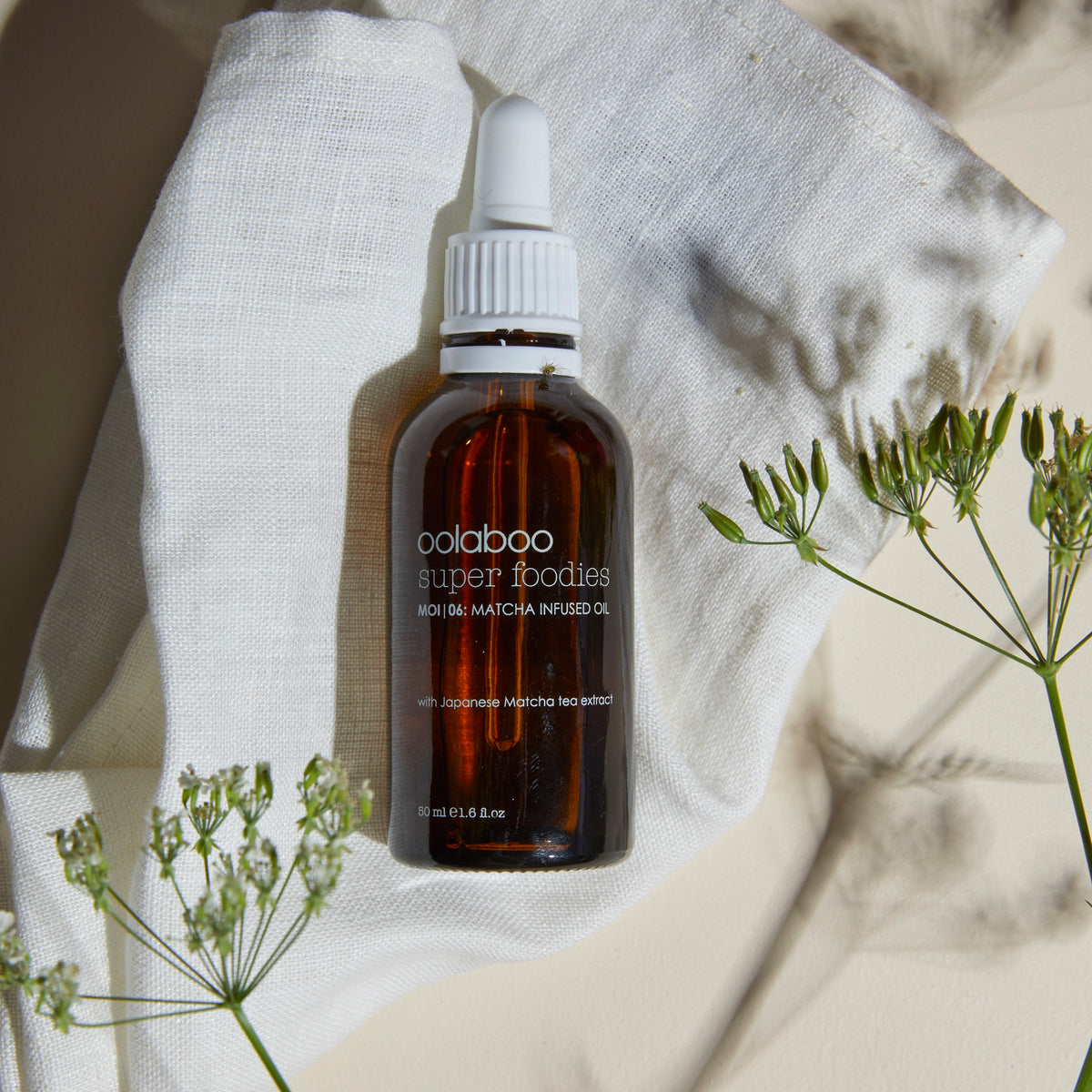 Oolaboo Super Foodies Matcha Infused Oil su telo di lino con fiori