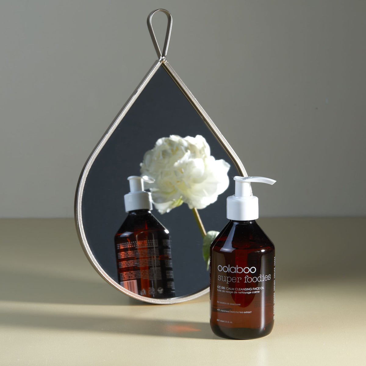 Oolaboo Super Foodies Calm Cleansing Face Oil davanti a uno specchio con peonia